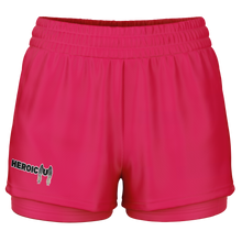 Coral athletic shorts with a double-layered leg design, featuring a small 'HEROIC U' graphic on the right leg, set against a plain white background.
